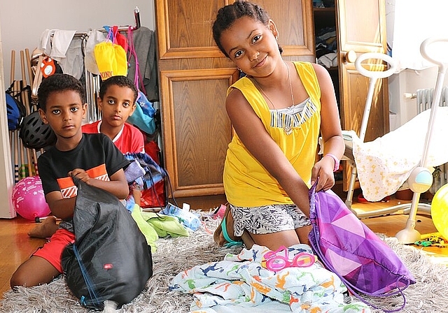 Perez, Barok und Barkot <em>(v. l.) packen in ihrem Zimmer in der Asylunterkunft in Neuenhof die Badesachen ein. (Melanie Bär)