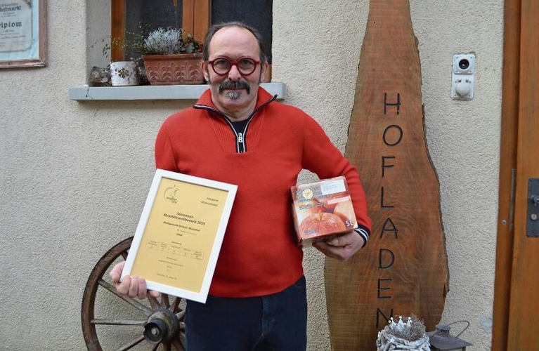 Stolz auf die Auszeichnung: Herbert Wohlgemuth posiert mit dem Zertifikat und einem Karton Süssmost vor dem Hofladen. Irene Hung-König