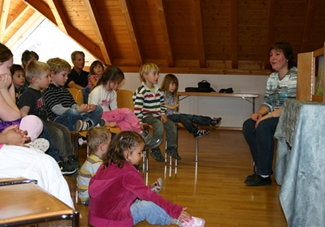 Gespannt lauschen die Kinder der Erzählung von Anita Szasz und betrachten die Bilder im Holzkoffer.Foto: mbo