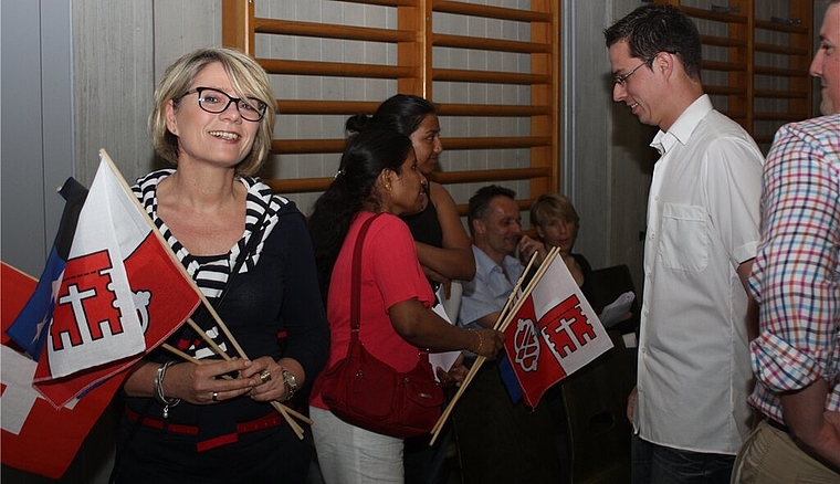 Elke Busse (l.) freut sich über ihre Einbürgerung und die Fahnen der Gemeinde.bär