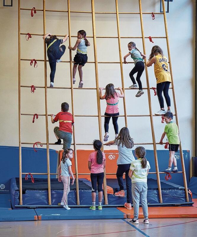 Die Kinder klettern die Wand hinauf in der Turnhalle.idée-Sport/Christian Jaeggi